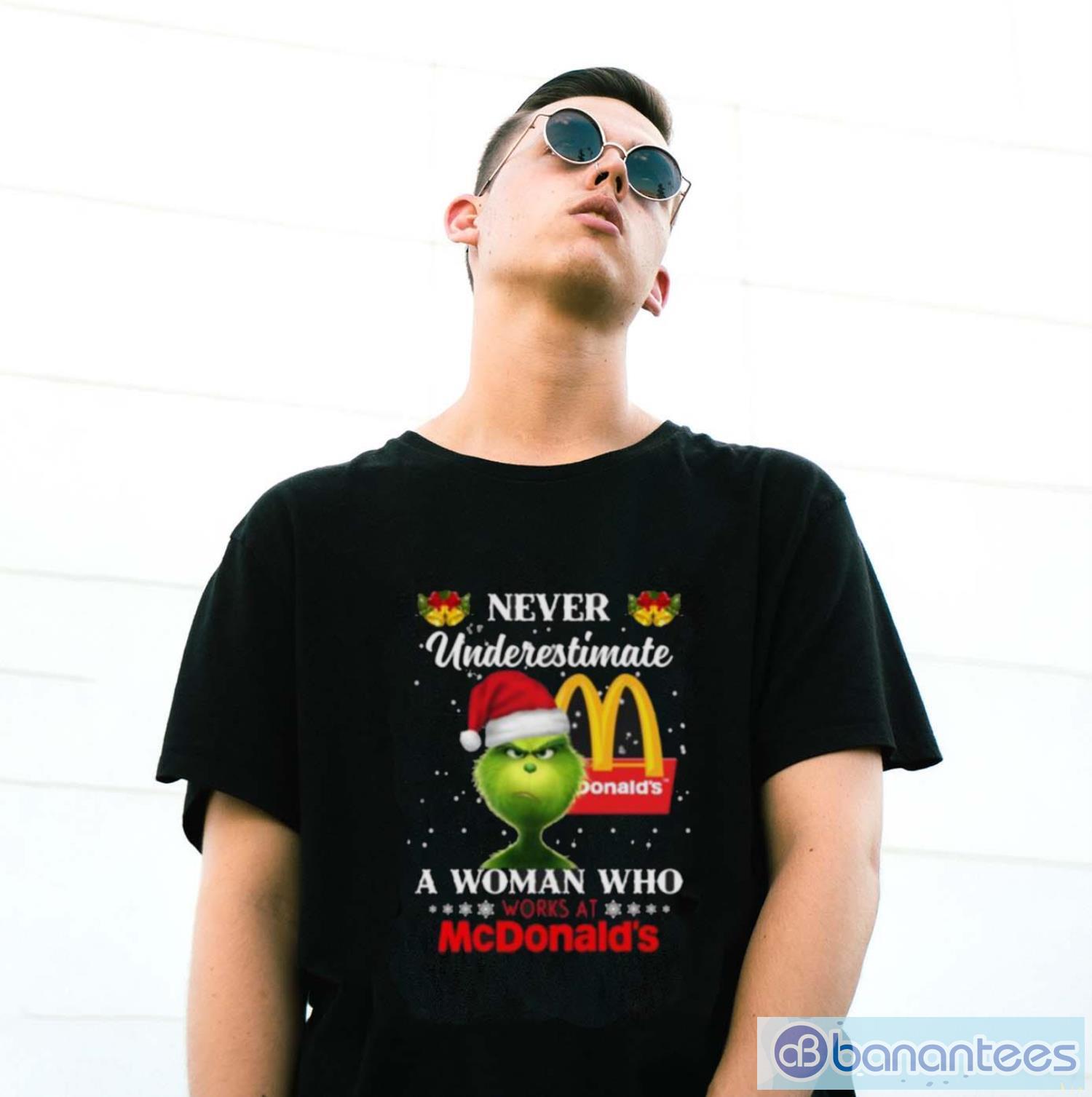 christmas 2023the grinch santa hat never underestimate a woman who works at mcdonalds shirt 2 image Christmas 2023The Grinch Santa Hat Never Underestimate a Woman who Works at McDonald’s shirt - G500 Gildan T-Shirt